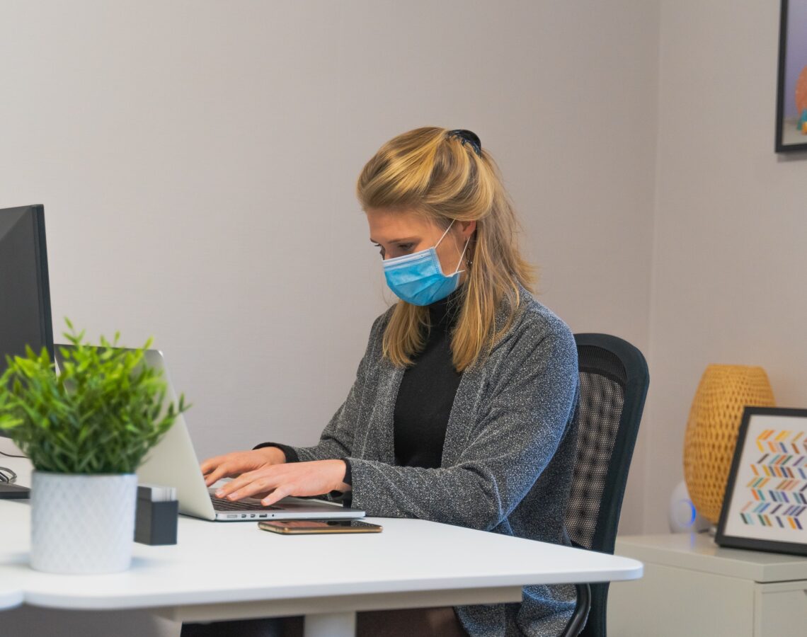 masked woman working in an office